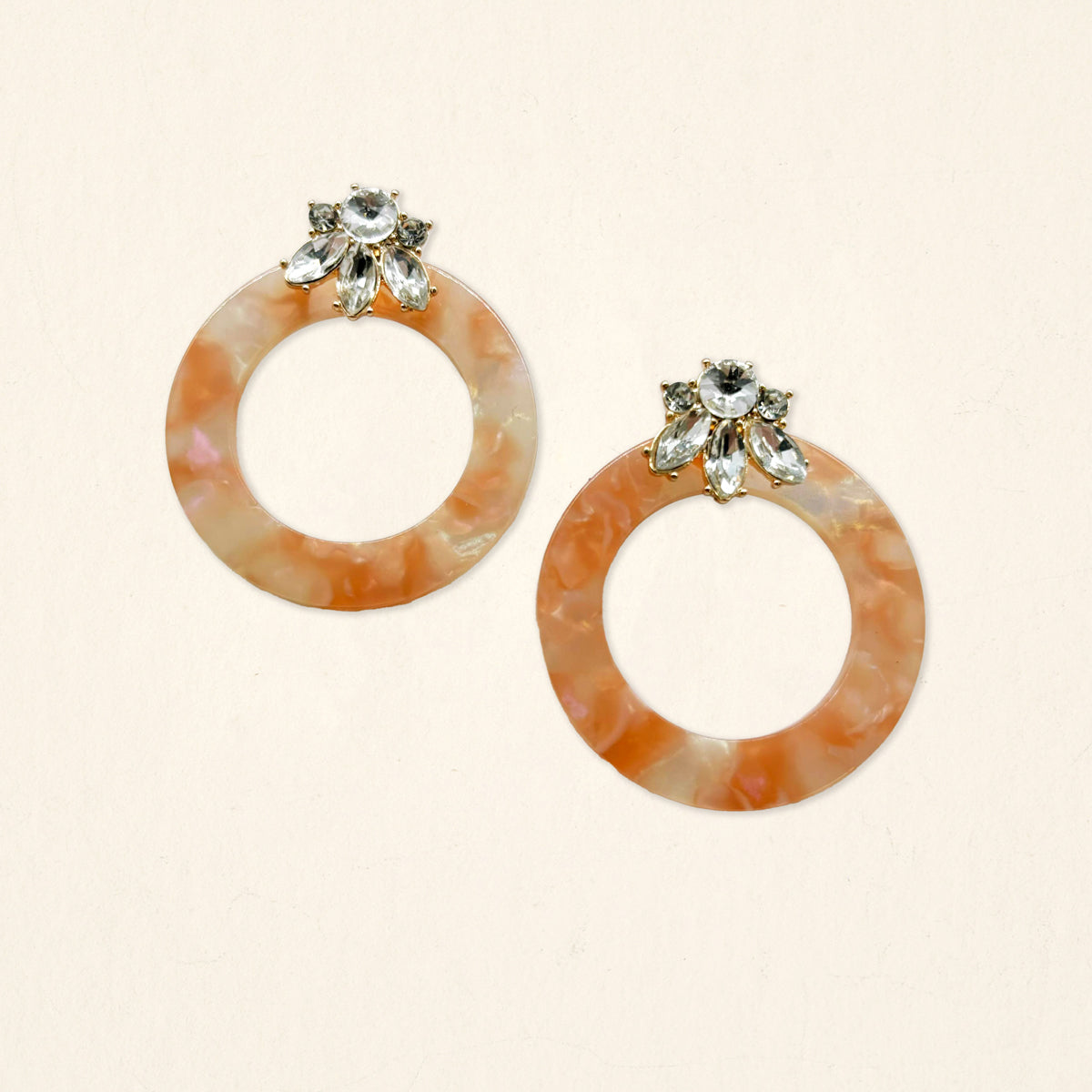 The Darling Effect’s Rose Quartz Glow Getter Earrings feature peach marbled hoops with a cluster of clear rhinestones, creating a lightweight statement piece that adds elegance to any outfit.