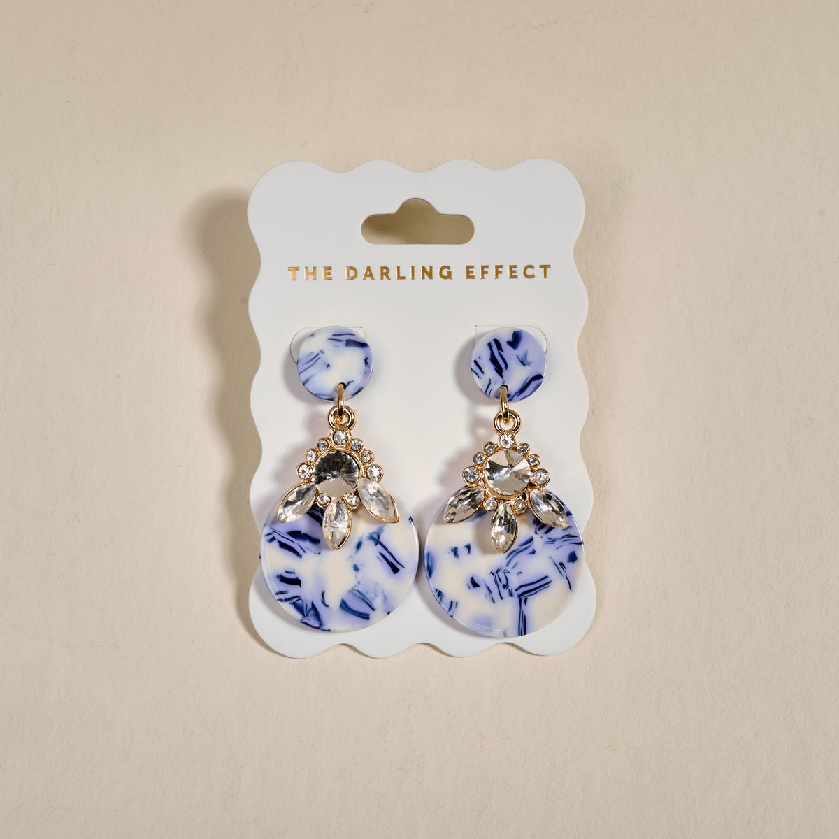 The Darling Effect’s Chinoiserie Flair Show Stopper Earrings feature blue and white marbled discs with clear rhinestones. Lightweight and modern, they add a unique, contemporary touch to any outfit.