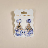 The Darling Effect’s Chinoiserie Flair Show Stopper Earrings feature blue and white marbled discs with clear rhinestones. Lightweight and modern, they add a unique, contemporary touch to any outfit.