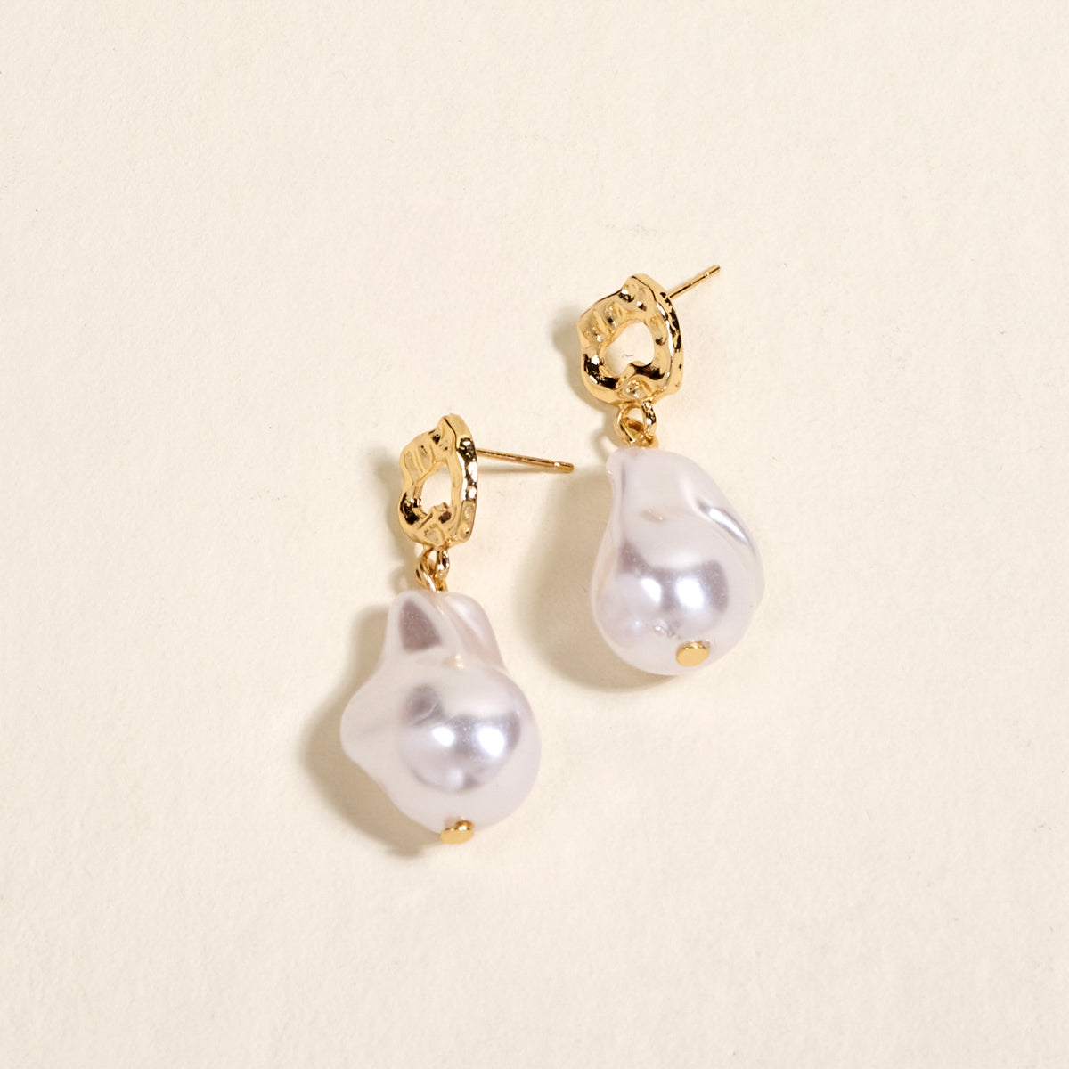 The Darling Effect’s Baroque Pearl Standout Earrings feature irregular white baroque pearls with a high-shine finish, displayed on a light surface—perfect for adding elegance to special occasion jewelry.