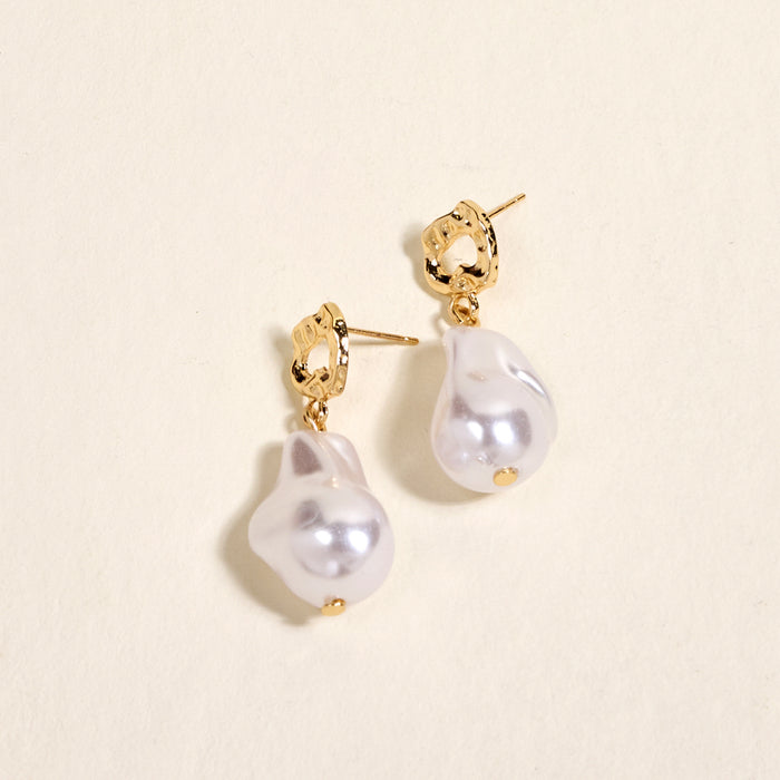 The Darling Effect’s Baroque Pearl Standout Earrings feature irregular white baroque pearls with a high-shine finish, displayed on a light surface—perfect for adding elegance to special occasion jewelry.