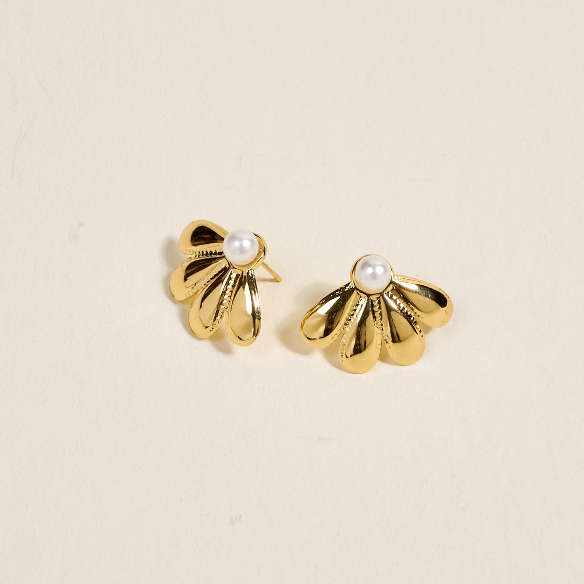 The Darling Effect's Daisy Doo Standout Earrings feature golden, petal-shaped fans with a lustrous finish and a central white pearl, shown on a light background—an elegant choice for special occasions.