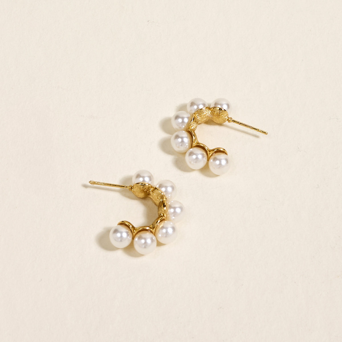 The Darling Effect's Power Pearl Standout Earrings feature gold hoops with a high-shine finish and clustered pearls, making an elegant jewelry statement.