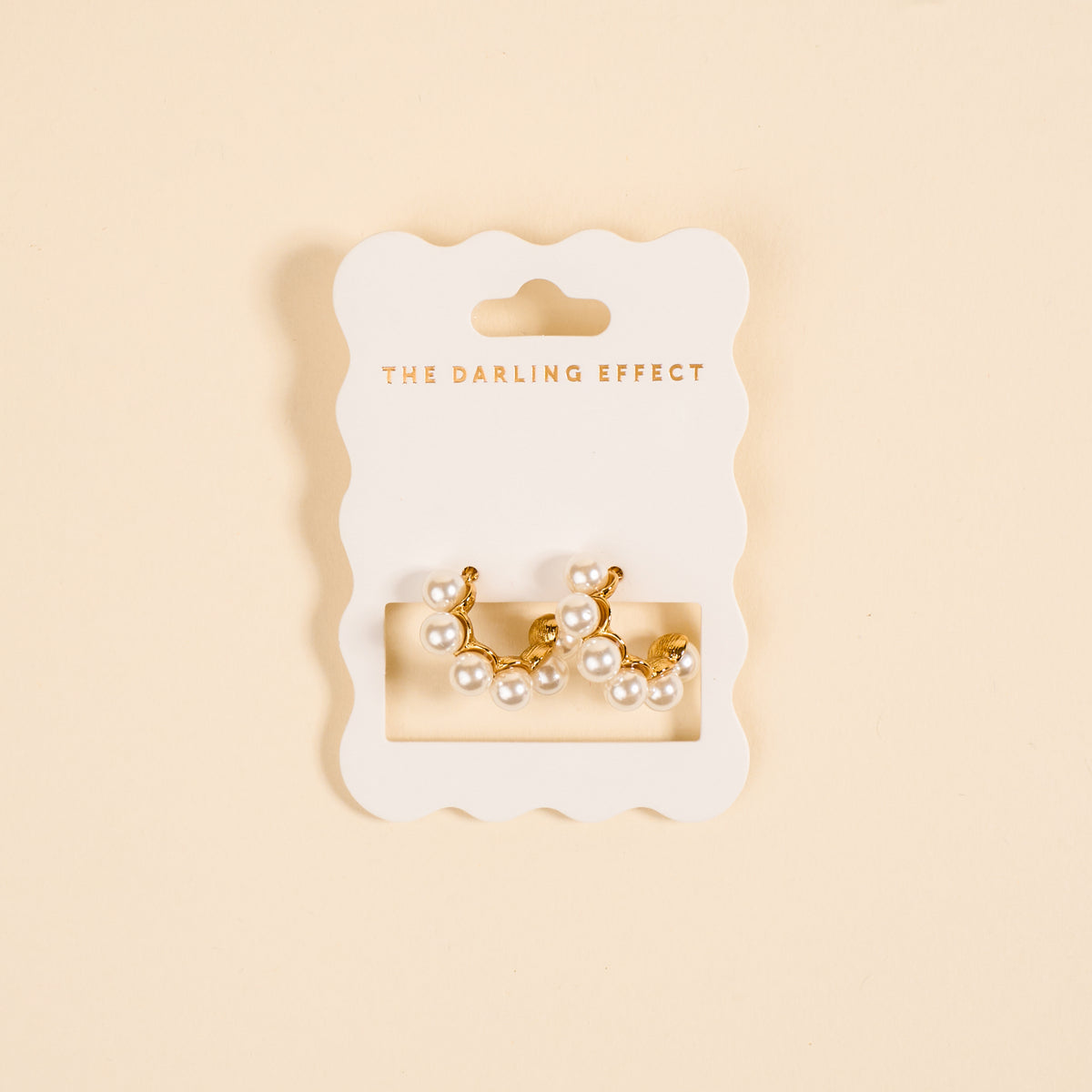 Elevate your style with Power Pearl Standout Earrings by The Darling Effect—gold-tone, high-shine earrings adorned with lustrous white pearls, presented on a scalloped THE DARLING EFFECT card with gold lettering on a cream background.