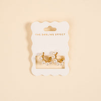 Elevate your style with Power Pearl Standout Earrings by The Darling Effect—gold-tone, high-shine earrings adorned with lustrous white pearls, presented on a scalloped THE DARLING EFFECT card with gold lettering on a cream background.