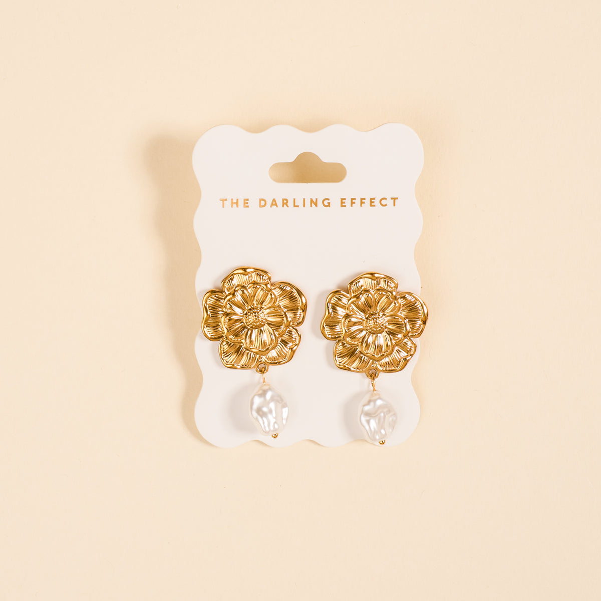 The Vintage Bloom Standout Earrings by The Darling Effect feature golden drops with pearls, displayed on a white scalloped card. Chic and elegant, they're a statement jewelry piece that stands out.