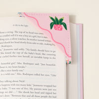 The Darling Effect's Book Shelfie Corner Keeper Fabric Bookmark features pink felt, quilted design, green and pink embroidered strawberry, and wavy stitching—an adorable gift for book lovers.