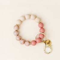 The Mauve Muse Hands-Free Keychain Wristlet by the-darling-effect features round silicone beads in cream, pink, and marbled hues, a gold keyring, lobster clasp, and a heart charm engraved with "hope changes" for stylish convenience.