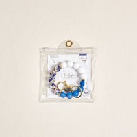The-darling-effect Notes of Navy Hands-Free Keychain Wristlet features blue floral silicone beads, gold hardware, and comes in a clear pouch for stylish, convenient carrying.
