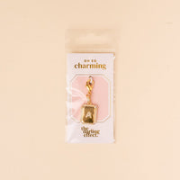 The-darling-effect’s A Jewelry Charm Initial Letter Gold features a gold-plated letter and clasp, attached to an “OH SO charming and the darling effect” card, all in a clear pouch—a perfect personalized jewelry piece.