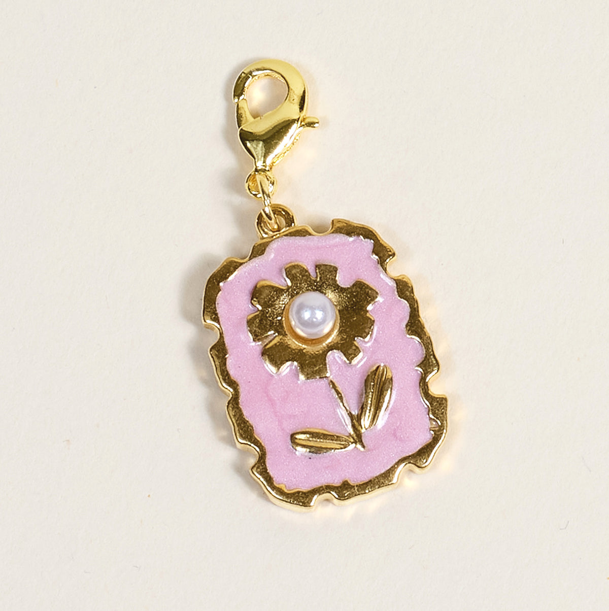 The Darling Effect’s Blushing Bloom Jewelry Charm Gold features a scalloped border, pink enamel background, flower design with gold accents, pearl-like center, and lobster clasp—ideal for your charm bar.