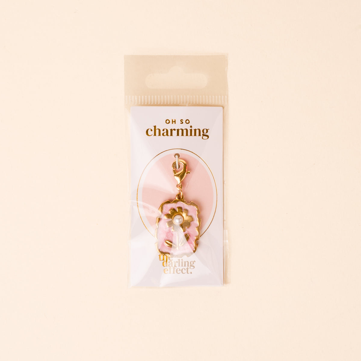 The Darling Effect’s Blushing Bloom Jewelry Charm Gold features gold and pink enamel with a bow and rhinestone, packaged on a light cream OH SO charming card in a clear bag—perfect for your charm bar or jewelry collection.