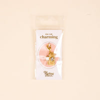 The Darling Effect Film Camera Jewelry Charm Gold features a crystal detail and comes attached to an "OH SO charming" card, packaged in a clear bag—perfect for adding to your personalized jewelry collection.