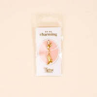 The Cowgirl Boot Jewelry Charm Gold by the-darling-effect comes attached to an "oh so charming" card, packaged in a clear sleeve with a beige background.