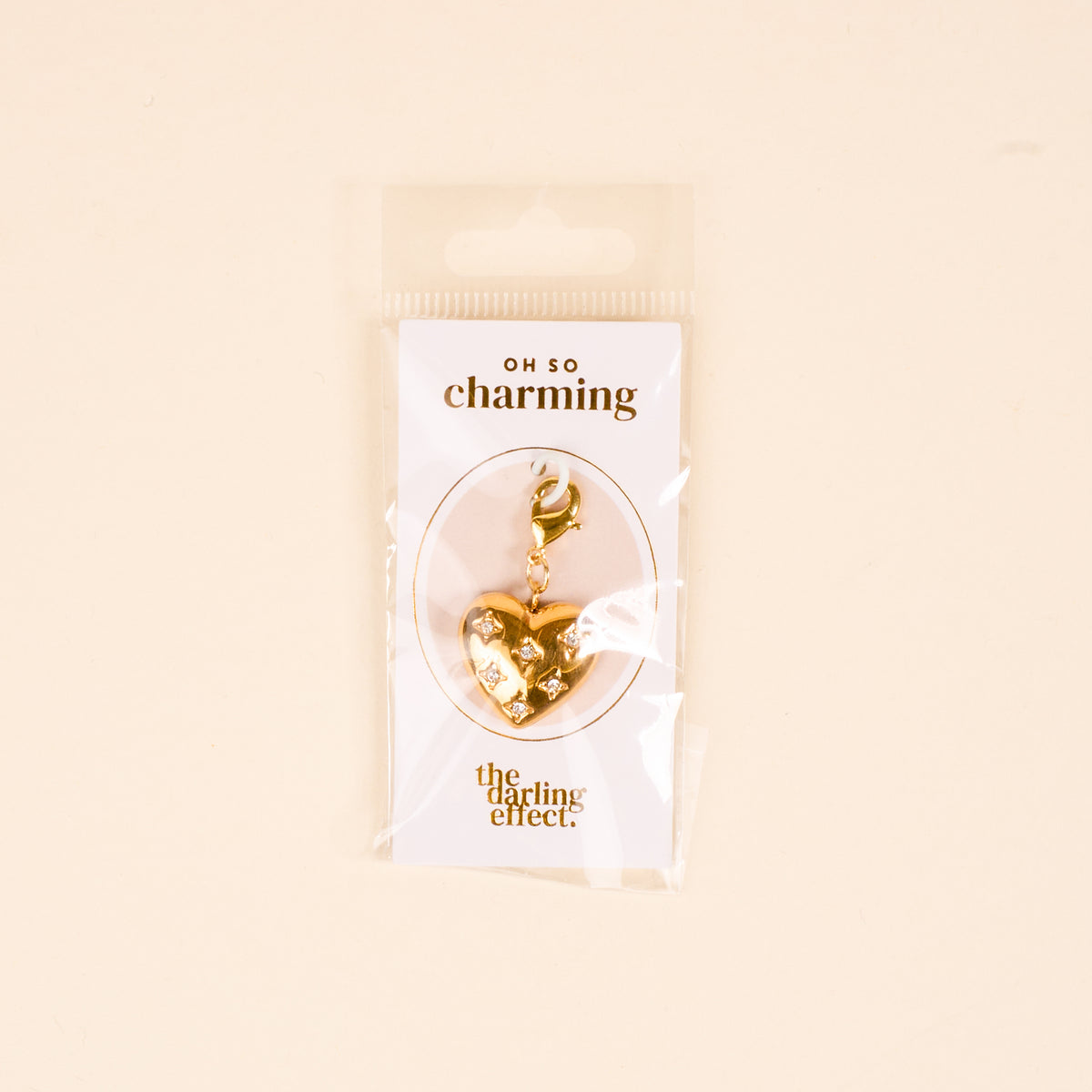 The Diamond Heart Jewelry Charm Gold by The Darling Effect features a gold, heart-shaped design with a clasp, packaged on an "OH SO charming" card—perfect for adding a meaningful touch to your charm bar.
