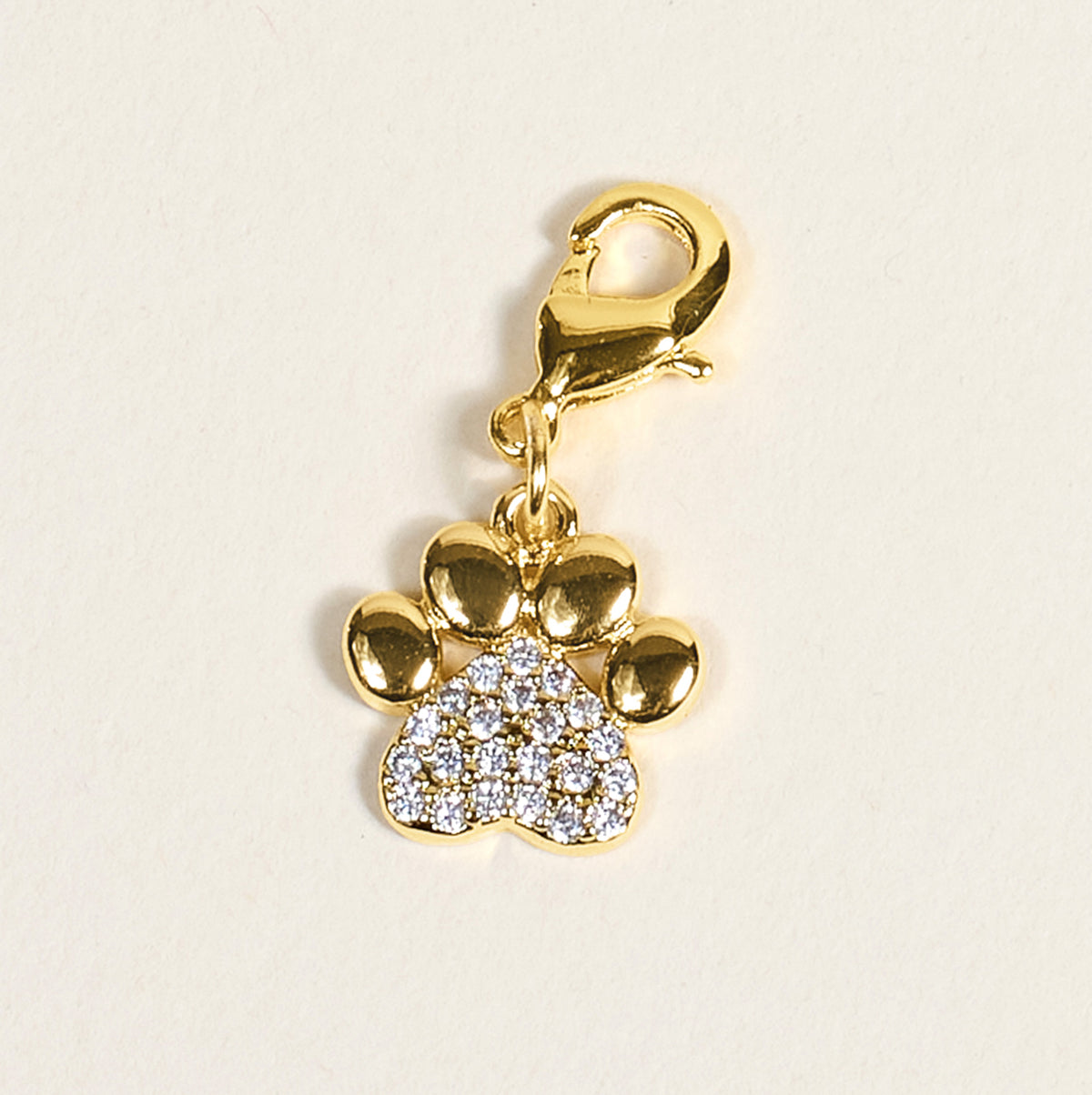 The Darling Effect’s Dazzled Paw Print Jewelry Charm Gold sparkles with clear stones and features a lobster clasp, making it easy to attach to your charm bar or favorite accessory.