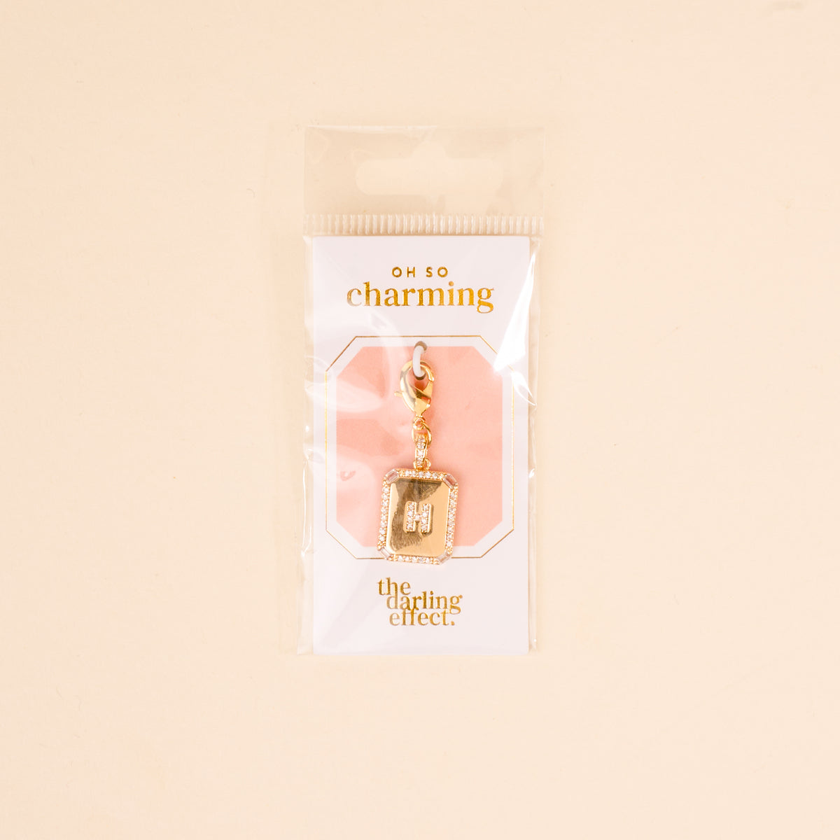 The H Jewelry Charm Initial Letter Gold by the-darling-effect features a gold-plated, rhinestone-encrusted letter H with a lobster clasp, packaged in plastic—ideal for adding personalized sparkle to your style.