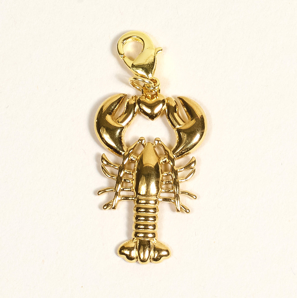The Darling Effect’s Lobster Love Jewelry Charm Gold features a shiny lobster shape with a clasp, ideal for charm bars or layering necklaces, shown on a plain white background.
