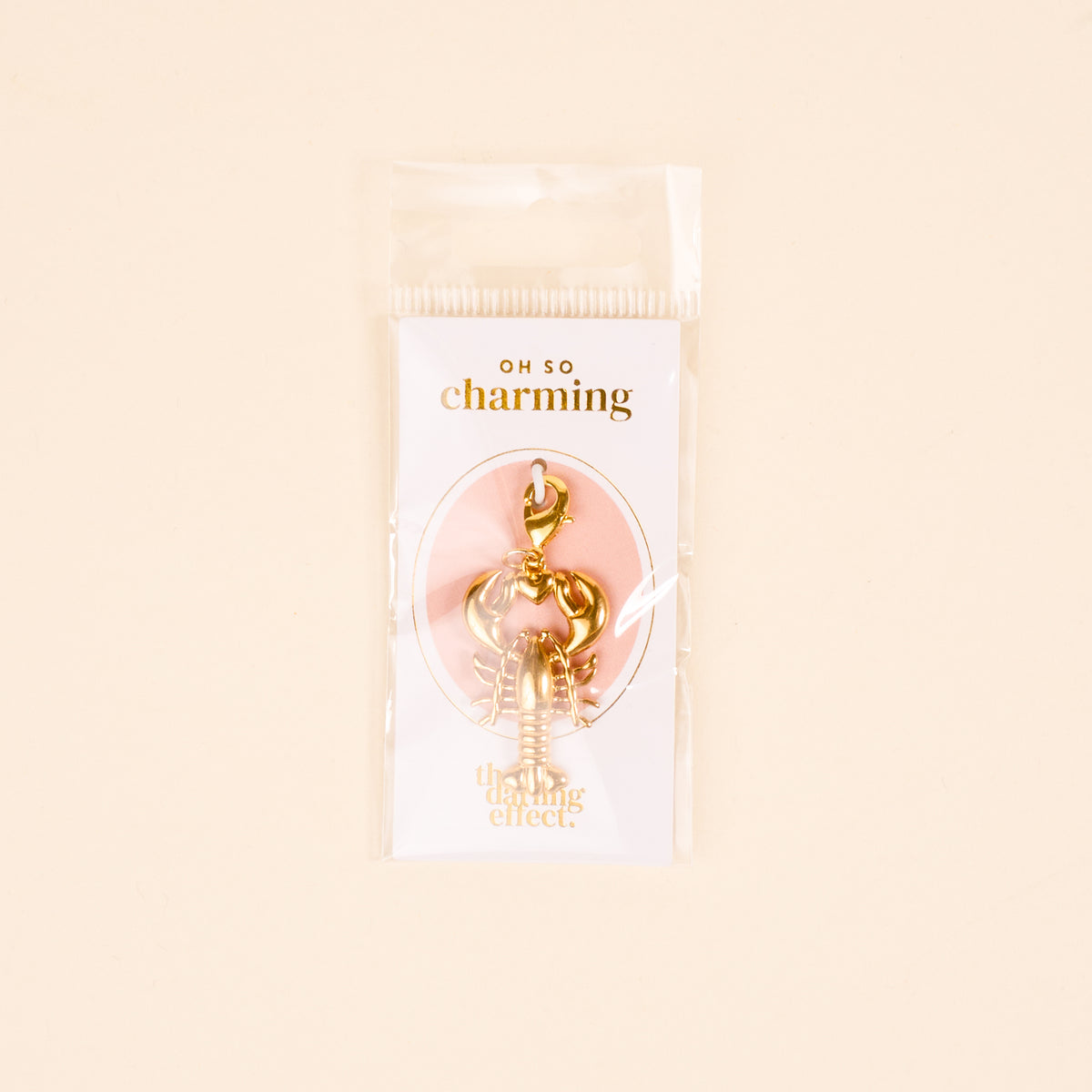 The Darling Effect's Lobster Love Jewelry Charm Gold features a lobster-shaped design with a clasp, packaged in a clear bag that reads "OH SO charming" and "The Darling Effect"—perfect for your charm bar or layering necklace.