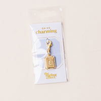 The-darling-effect L Jewelry Charm Initial Letter Gold features a gold-plated brass charm with rhinestone border, lobster clasp, and comes attached to an OH SO charming packaging card in a clear plastic bag.