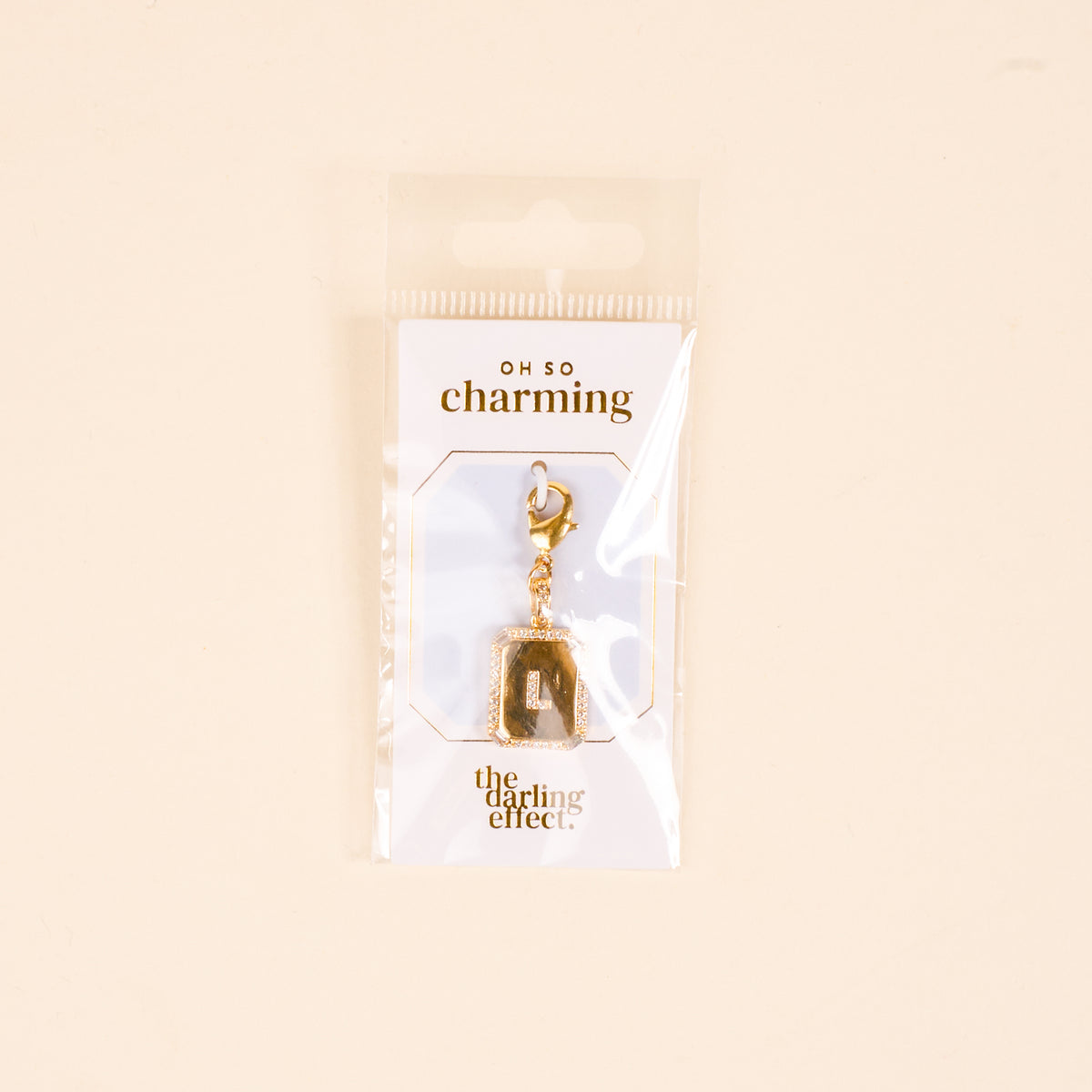 The-darling-effect L Jewelry Charm Initial Letter Gold features a gold-plated brass charm with a diamond-encrusted border and clasp, packaged in plastic with "OH SO charming" and "the darling effect."—perfect for personalized jewelry lovers.