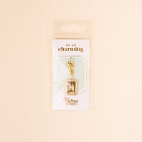 The M Jewelry Charm Initial Letter Gold by the-darling-effect features a gold-plated charm attached to a lobster clasp, displayed on white Oh So Charming packaging—an ideal gift for personalized jewelry lovers.