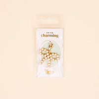 The Darling Effect Pretty in Pearl Bow Jewelry Charm Gold features pearls and a clasp, ideal for charm jewelry lovers. Presented on an OH SO charming card with The Darling Effect logo, in clear packaging.