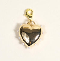 The Darling Effect’s Pearl Lined Heart Jewelry Charm Gold features a gold heart shape, small white pearls along the edge, and a lobster clasp—perfect for charm jewelry or your own charm bar. Photographed on a light beige background.