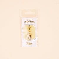 The-darling-effect's V Jewelry Charm Initial Letter Gold is a gold-plated rectangular pendant with the letter V, packaged in clear plastic—perfect for fans of personalized and Initial Letter Jewelry Charms.