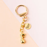 The F Bubble Letter Keychain Bag Charm by the-darling-effect features a gold bubble “F,” lobster clasp, and engraved round tag—this personalized accessory pops against a peach and light pink background.