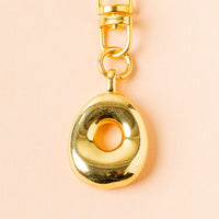 The O Bubble Letter Keychain Bag Charm by the-darling-effect features a gold charm on a gold clasp and chain—ideal for adding a personalized touch to your accessories or bag.