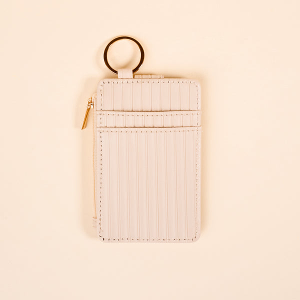 The Darling Effect Oat Ripple Ridge Keychain Wallet features a light cream color, vertical ribbed texture, gold zipper, and keychain ring—doubles as a coin holder. Shown on a cream background.