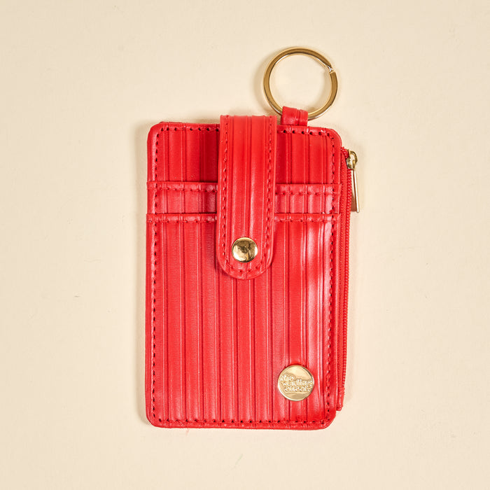 The Darling Effect Red Ripple Ridge Keychain Wallet features card slots, a gold keyring, snap button closure, side zippered coin holder, and a gold emblem at the bottom right corner, shown on a beige background.