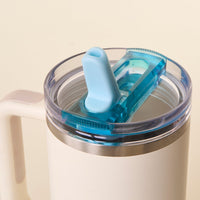 A close-up of the-darling-effect Blue 40 oz Lifestyle Flip Straw Lid shows a white insulated travel mug with a clear, leak-resistant flip straw lid and blue spout against a plain light background.
