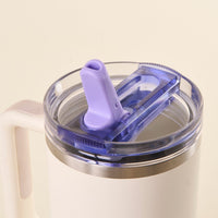 Close-up of the-darling-effect Periwinkle 40 oz Lifestyle Flip Straw Lid: a white insulated lid with a purple pull-tab, leak-resistant clear plastic cover, silver rim—ideal for easy hydration on the go.