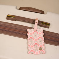 The Darling Effect's Everbloom Dusty Rose Jetsetter Luggage Tag, featuring scalloped edges, gold hardware, and a privacy flap, is shown attached to a cream Delsey suitcase handle—a charming travel accessory.