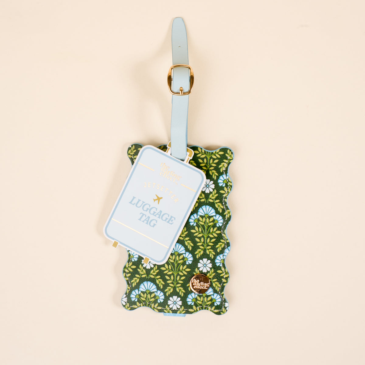 The Darling Effect Everbloom Forest Green Jetsetter Luggage Tag features a scalloped edge, green floral pattern, blue privacy flap, gold buckle, and a blue card labeled "Luggage Tag" for style and security.