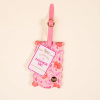 The Darling Effect's Poppin' Petals Hot Pink Jetsetter Luggage Tag features a scalloped edge, floral pattern, pink strap with gold buckle, privacy flap, and “Jetsetter” text for the perfect stylish suitcase accessory.