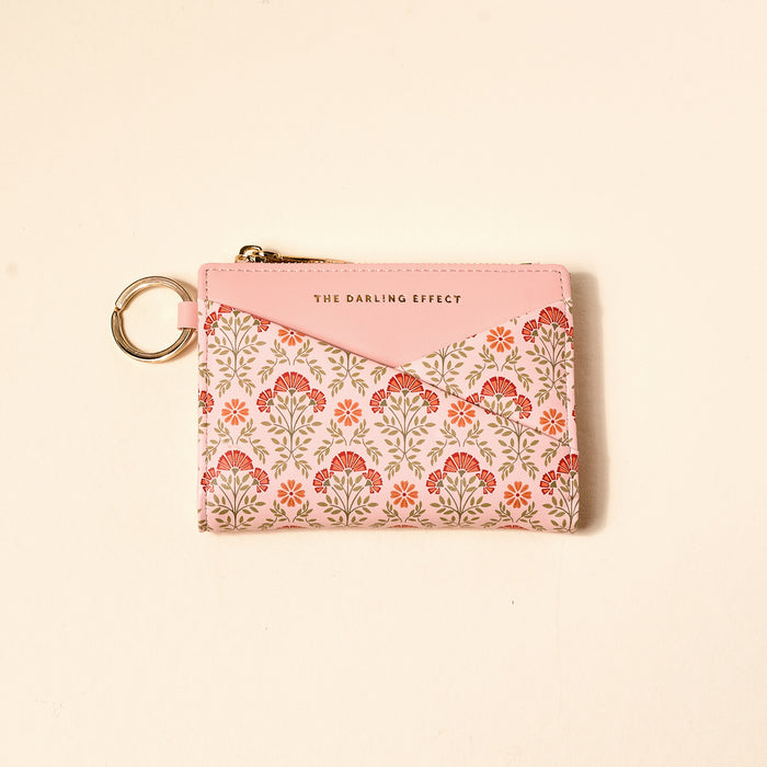 The Darling Effect Everbloom Dusty Rose Luxe Pocket Wallet features a floral criss-cross design, gold zipper, keychain, vegan leather, and “THE DARLING EFFECT” in gold on the top pink section.