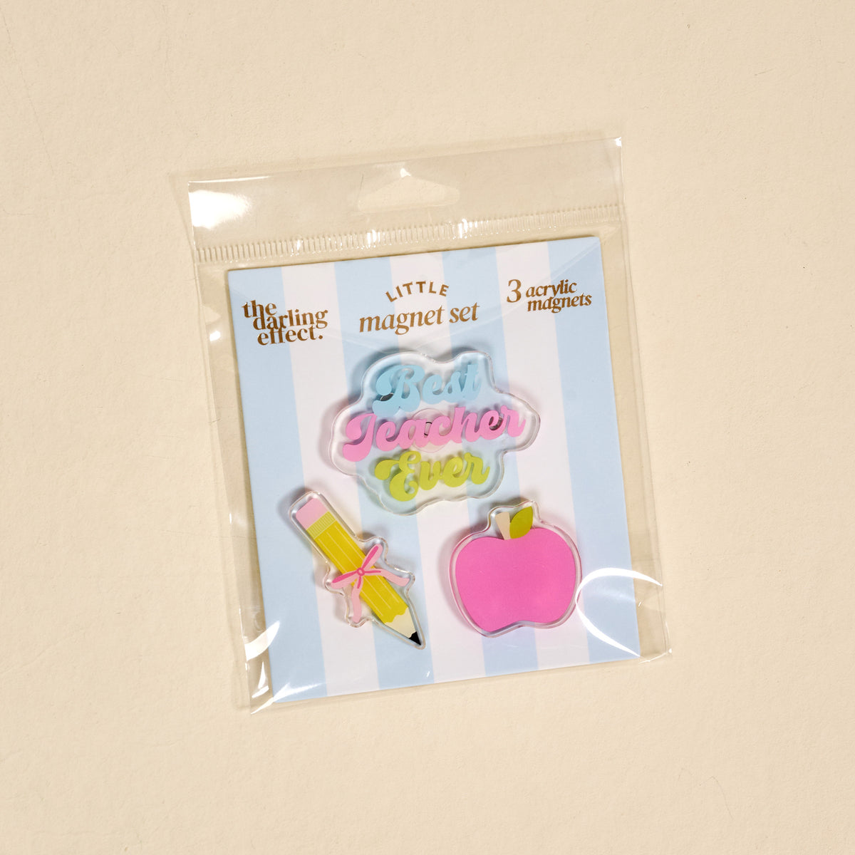 Introducing the Best Teacher Ever Little Magnet Set by The Darling Effect. This set includes three charming acrylic magnets: a yellow pencil with a pink bow, a pink apple, and a pastel magnet featuring the phrase “Best Teacher Ever.” Perfect for brightening up any space, these decorative accents come stylishly labeled as the LITTLE magnet set.