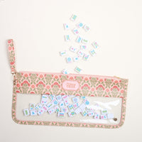 The Darling Effect’s Everbloom Dusty Rose Mahjong Tile Keeper Pouch features a transparent front and a label reading "Mahjong Tiles," stylishly displaying illustrated tiles spilling out—perfect for chic Mahjong tile storage.