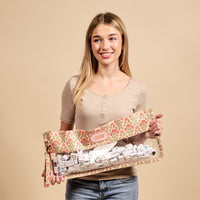A blonde woman holds The Darling Effect's Everbloom Dusty Rose Mahjong Tile Keeper Pouch, a transparent floral accessory ideal for stylishly storing Mahjong tiles.