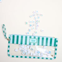 The Darling Effect's Sicily Stripes Teal Mahjong Tile Keeper Pouch lies open, with colorful mahjong tiles spilling out onto a light beige surface.