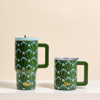 Two Everbloom Forest Green 14 oz Insulated Mugs by The Darling Effect, featuring handles, lids, and a blue and white floral design, sit side by side on a white surface against a light beige background.