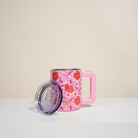 The Darling Effect's Poppin' Petals Hot Pink 14 oz Insulated Mug has double-wall insulation, a large handle, and a floral red/pink pattern. Photographed on a white surface with its clear plastic lid; plain beige background.