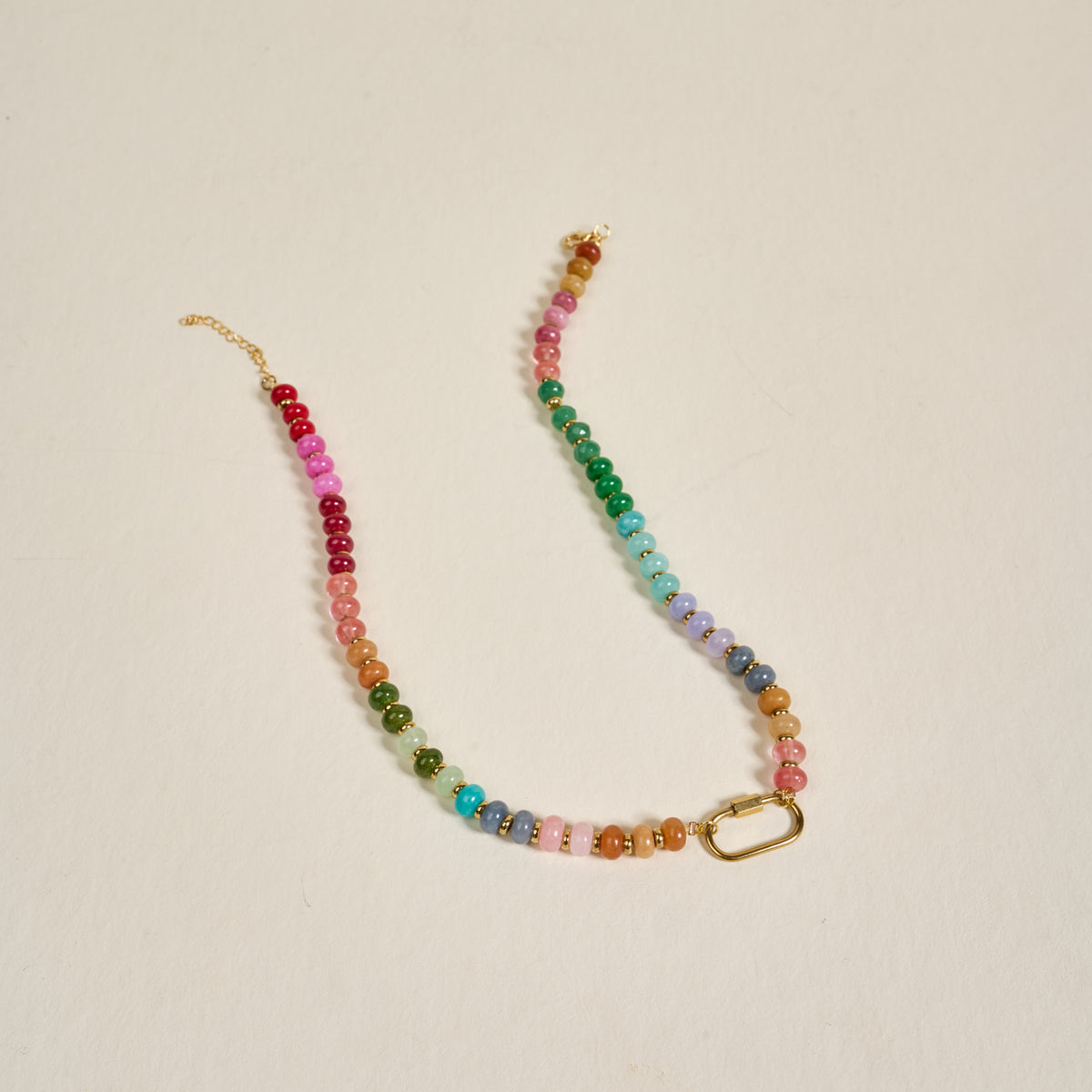 The Darling Effect’s Color Crush Stone Candy Necklace features small, round, multicolored beads in a gradient with a gold chain clasp and rectangular link—perfect for everyday wear, shown on a plain light background.