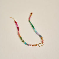 The Darling Effect’s Color Crush Stone Candy Necklace features small, round, multicolored beads in a gradient with a gold chain clasp and rectangular link—perfect for everyday wear, shown on a plain light background.