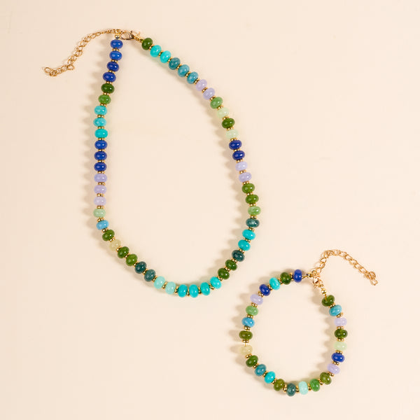 The Darling Effect’s True Blues Stone Candy Necklace features alternating blue, green, and light purple stone beads with an adjustable gold chain—playful and perfect for any occasion. Displayed on a light beige background.