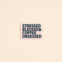 The Darling Effect’s Stressed, Blessed, & Coffee Obsessed Mix & Match Iron-On Patch features dark teal text on pink with a white outline—perfect for customizing jackets or bags with colorful flair.