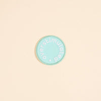 The Darling Effect's Overstimulated Mix & Match Iron-On Patch features a circular teal design with white "overstimulated" text embroidered around the edge. Personalize it with your favorite designs for a unique look.